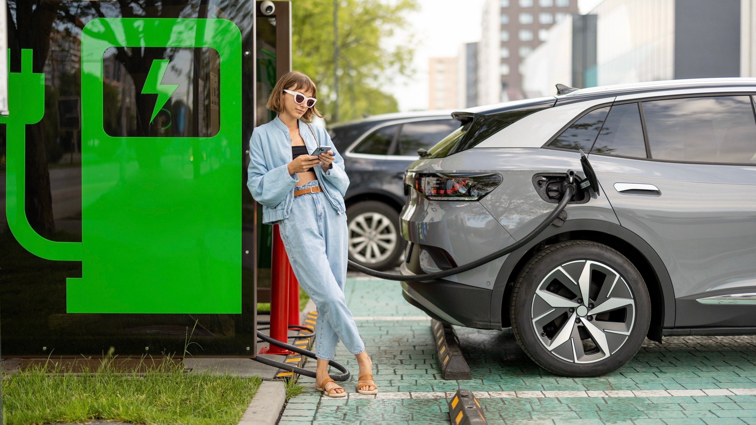Une femme qui attend le rechargement de sa voiture hybride.